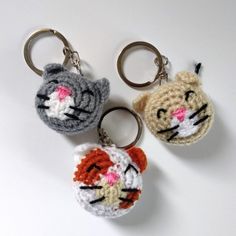 three crocheted keychains with cats on them sitting next to each other