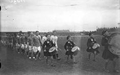 a group of people that are standing in the grass with some kind of drum behind them