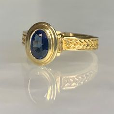 A modern and timeless vintage 14k yellow gold ring featuring an oval shaped sapphire weighing 0.95 carats securely set in a tiered bezel which elevates the stone above the finger with hand crafted detailing along the band. *Ring size: US 6 1/2 * Ring weight: 4.03 grams Classic Oval Cabochon Sapphire Ring With Bezel Setting, Classic Sapphire Ring With Oval Cabochon Bezel Setting, Classic 14k Gold Sapphire Oval Cabochon Ring, Classic Yellow Gold Sapphire Ring Oval Cabochon, Classic Oval Sapphire Ring, Classic Oval Sapphire Ring With Polished Finish, Elegant Sapphire Signet Ring, Gold Oval Cabochon Sapphire Ring For Formal Occasions, Gold Sapphire Ring With Oval Cabochon For Formal Events