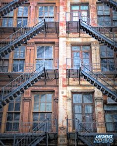 an old building with many windows and fire escape stairs on the outside, as seen from below