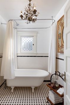 a white bath tub sitting under a chandelier in a bathroom