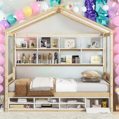 a room with balloons, bookshelves and a bed in the middle that has a doll house on it