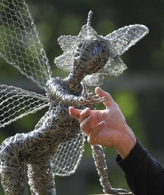 a person is holding up a wire sculpture