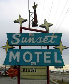 an old motel sign with the word sunset on it's side and stars above it