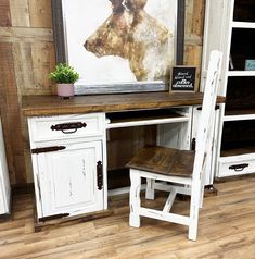 an old desk and chair are sitting in front of a framed cow head on the wall