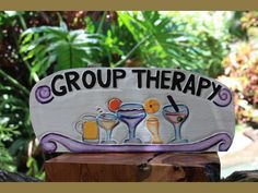 a group therapy sign sitting on top of a wooden post in front of some trees