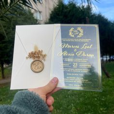 a person holding up a wedding card and brooch