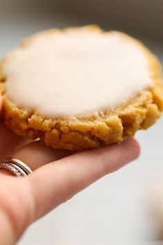 a close up of a person holding a small cookie with icing on it's side