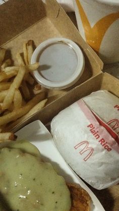 an open box with french fries and a burger on it next to a cup of sauce