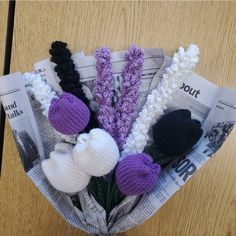 crocheted flowers are placed in a newspaper holder