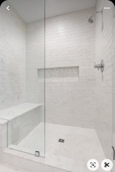 a walk in shower sitting next to a white tiled wall and counter top under a mirror