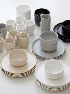 a table topped with lots of white and black plates, cups and saucers on top of each other