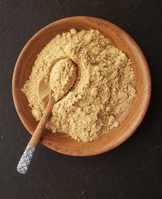 a wooden bowl filled with powder and a spoon