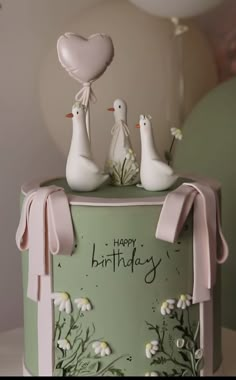 a birthday cake with three birds on top and a balloon in the shape of a heart