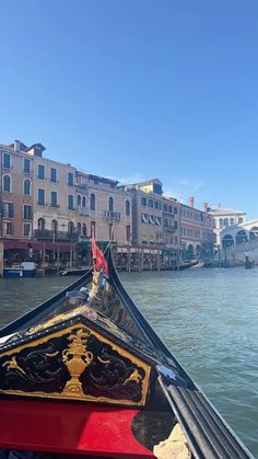 the back end of a boat traveling down a river in front of buildings and bridge