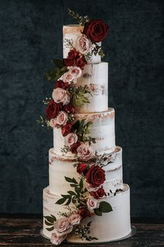 a three tiered cake with red flowers on top