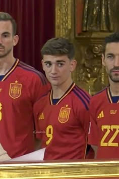 three soccer players are standing in front of a gold framed photo with their name on it