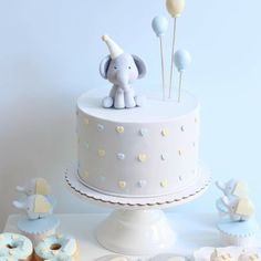 an elephant cake and cupcakes on a table next to it's fondant decorations