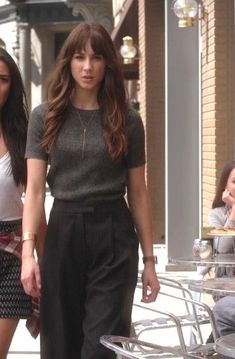 two young women walking down the street in high rise pants and t - shirt tops