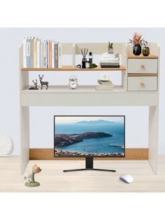 a computer desk with a monitor and books on it