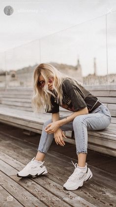 a woman sitting on top of a bench next to a wooden floor and wearing white sneakers