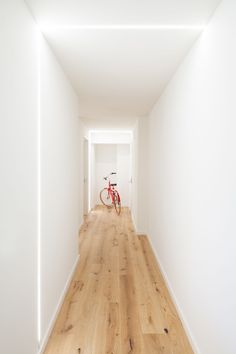 an empty hallway with a bike parked in the middle and light wood flooring on both sides