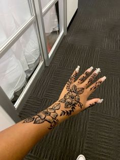 a woman's hand with hendix and flowers on it, next to a window