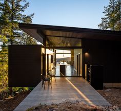 a wooden walkway leading to a black house in the middle of some trees and grass