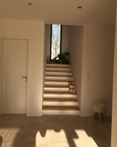 an empty room with stairs leading up to the top floor and light coming in through the window