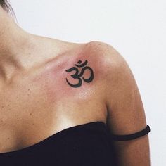 a woman with a tattoo on her shoulder that has an om symbol in the middle