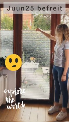 a woman standing in front of a window with an emoticive face drawn on it