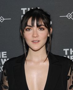 a close up of a person wearing a black dress and posing for the camera on a red carpet