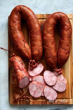 two sausages and three slices of ham on a cutting board next to each other