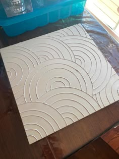 a piece of white tile sitting on top of a wooden floor next to plastic containers