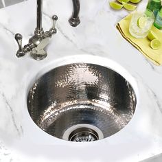 a stainless steel sink in a white marble counter top with limes on the side