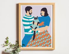 two people are holding a cat in front of a white wall with a potted plant