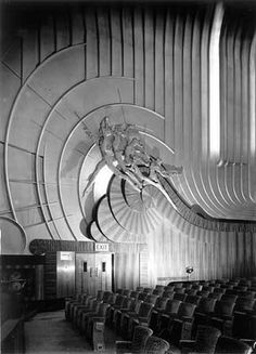 an empty auditorium with rows of chairs in front of the ceiling and large circular artwork on the wall