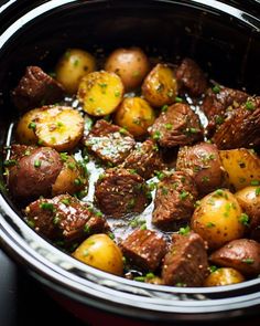 cooked potatoes and meat in a crock pot with parsley on the side, ready to be eaten