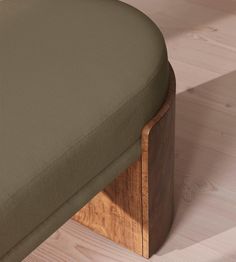 a close up view of a wooden bench with green fabric on the seat and back