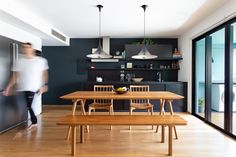 a dining room table and bench in front of an open kitchen with sliding glass doors