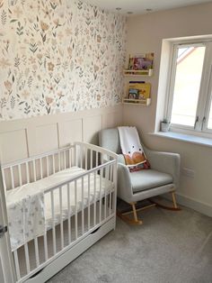 a baby's room with a rocking chair, crib and wallpaper on the walls