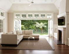 a living room with a large couch and fireplace in the corner, surrounded by windows