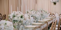 a long table is set with white flowers and candles for an elegant wedding reception at the four seasons resort