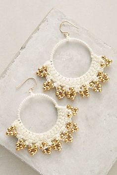 two pairs of white and gold beaded hoop earrings on top of a marble slab