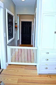 an empty hallway leading to a black door and white cabinet with drawers on either side