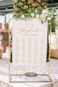 a wedding seating sign with flowers and greenery on it for guests to sit down