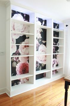 a white bookcase with flowers painted on the front and back sides, along with wooden flooring