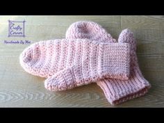 a pink knitted mitten sitting on top of a wooden table next to a pair of gloves