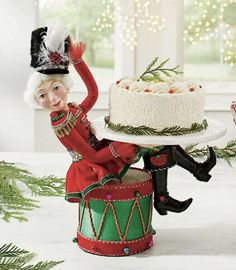 a small figurine sitting on top of a cake in front of a christmas tree