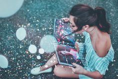 a woman is sitting on the ground and looking at her laptop screen with bubbles coming out of it